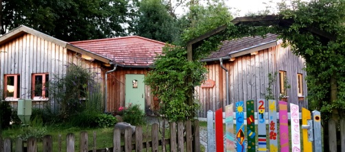 Verwilderter Garten mit buntem Gartentor zum Waldorfkindergarten